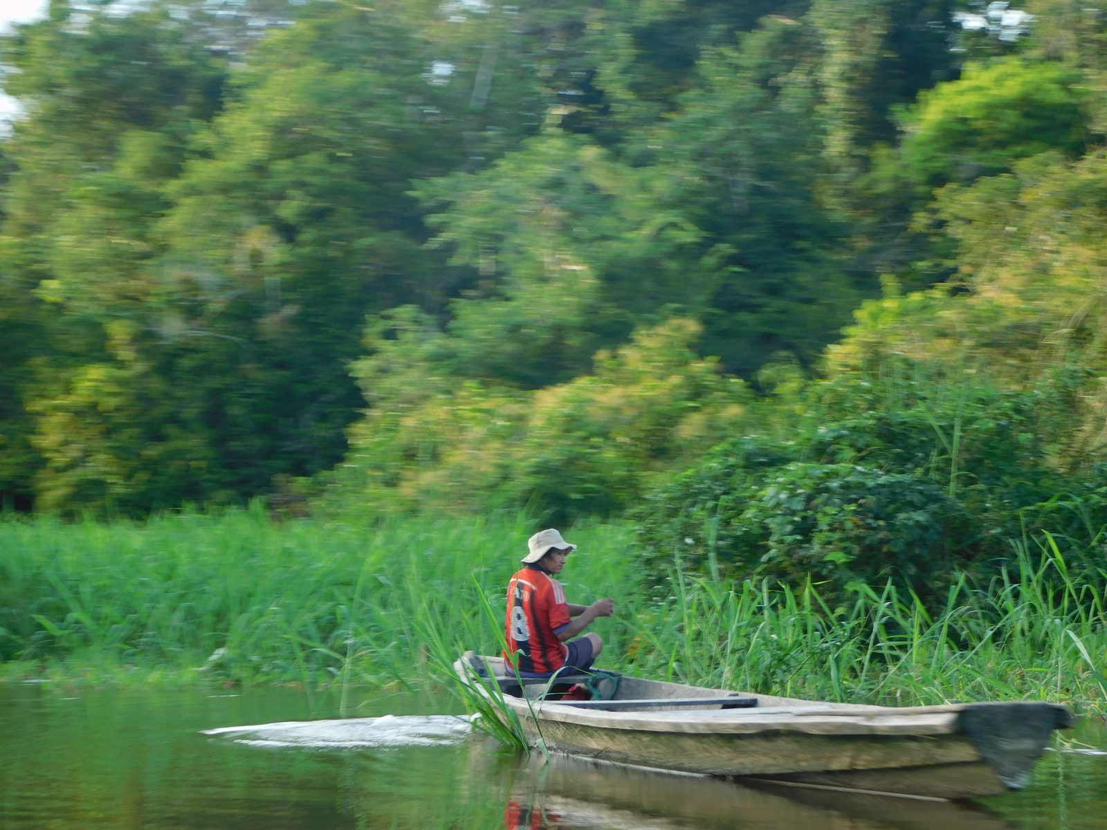 Homme pagayant en pirogue traditionnelle sur une rivière amazonienne