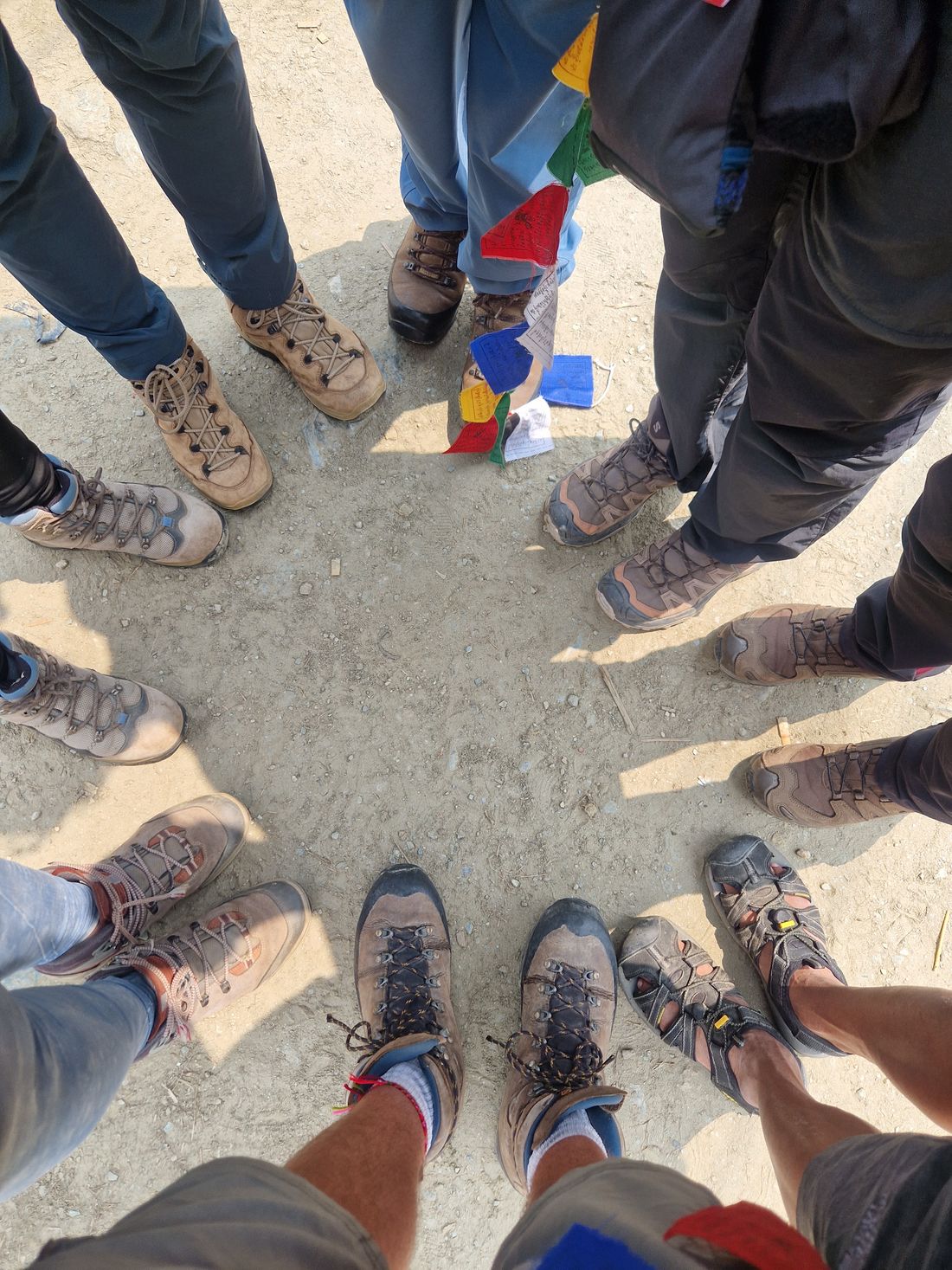 Un cercle de marcheurs en chaussures de randonnée, avec des drapeaux de prière tibétains