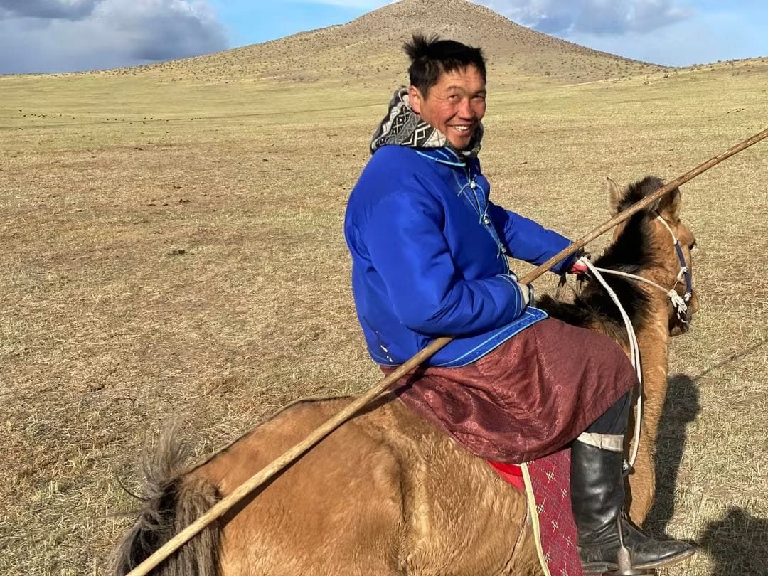 Dalaï, guide mongol souriant, à cheval dans la steppe