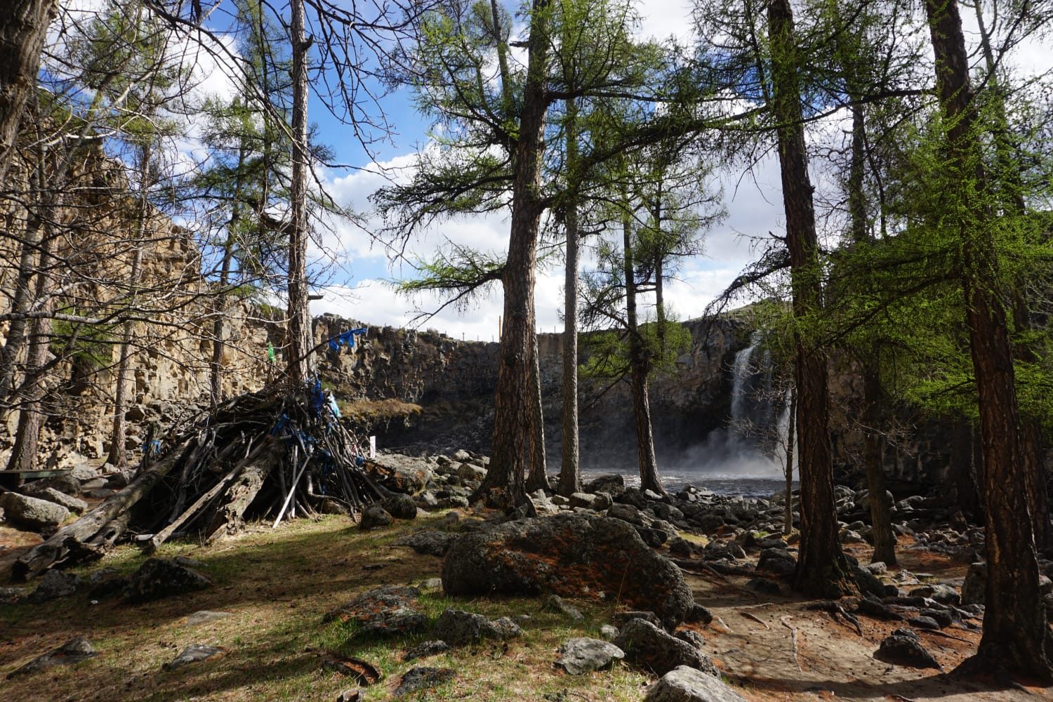 Cairn de pierres orné de rubans de prière près d'une cascade, Mongolie
