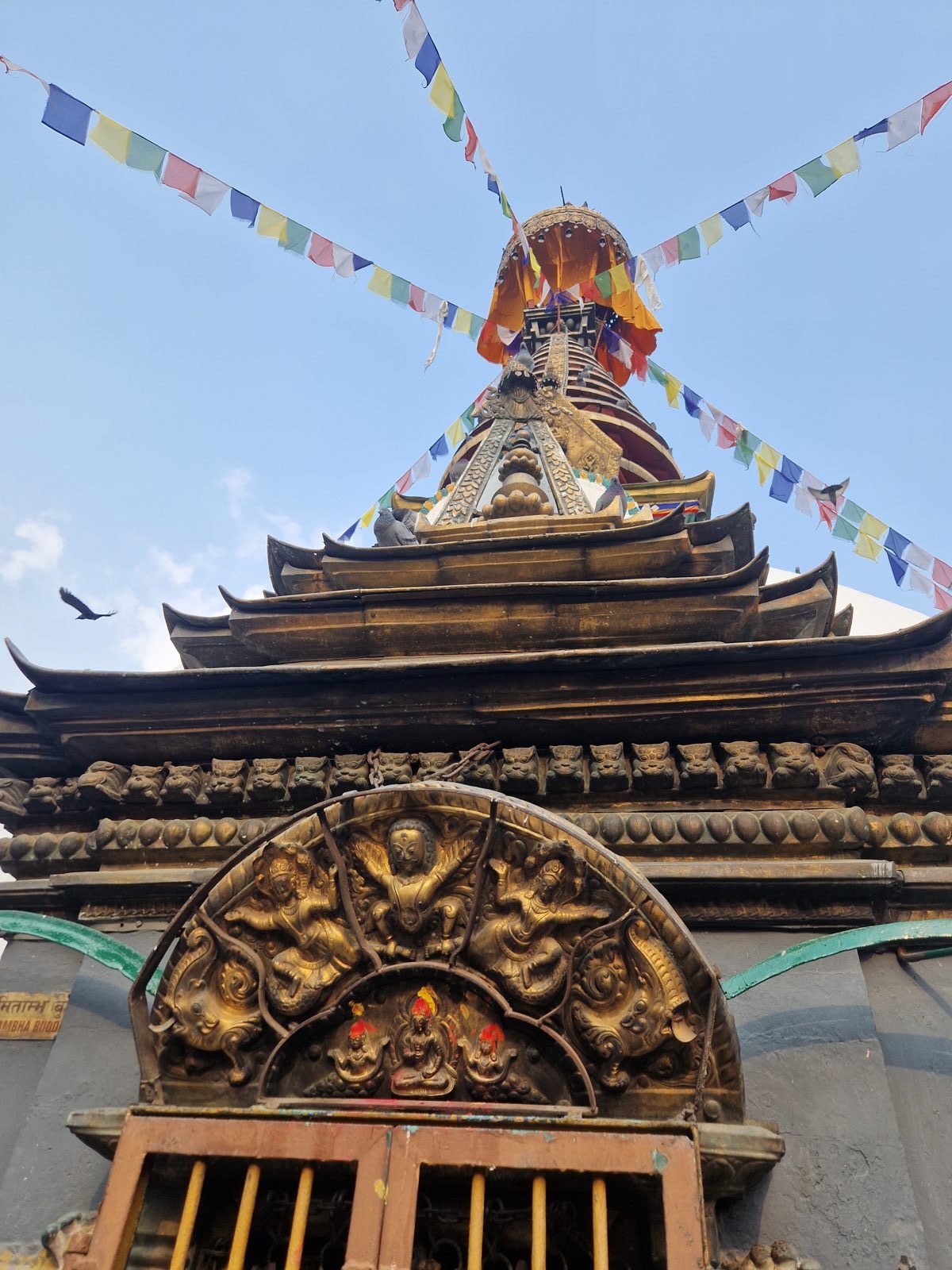 Sommet doré d'un stupa orné de drapeaux de prière