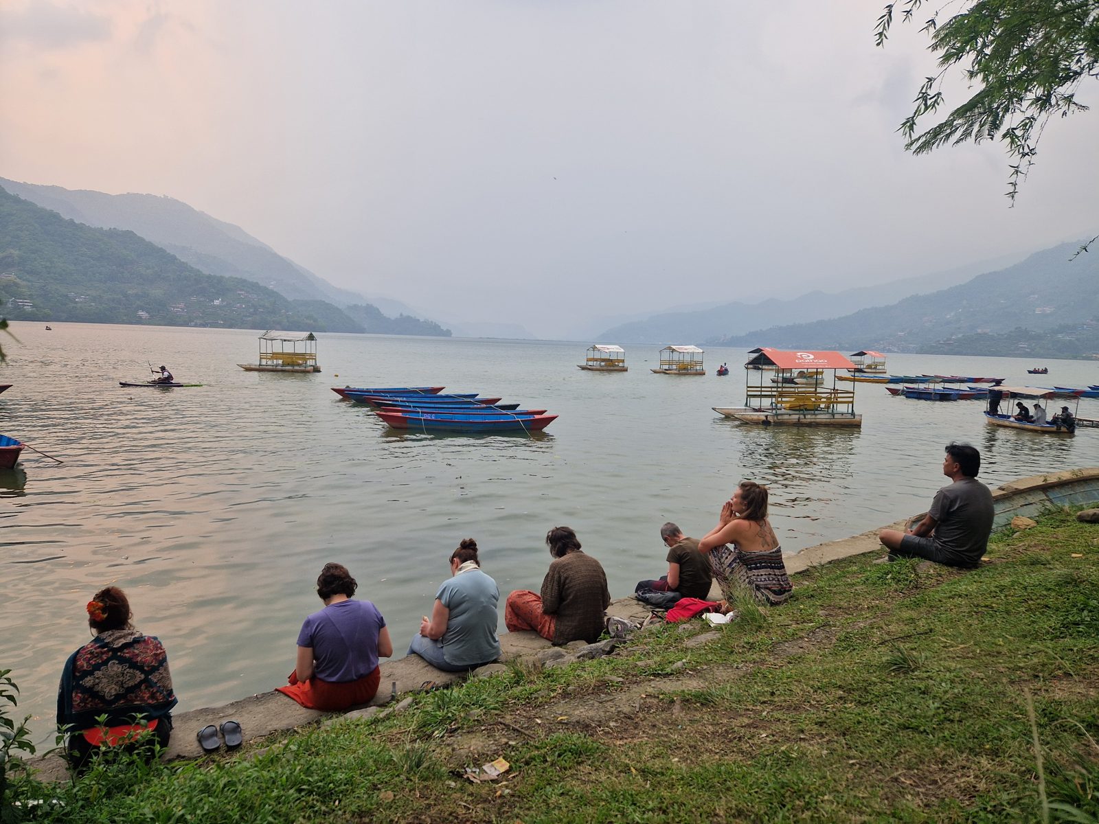 Groupe en méditation au bord du lac Phewa, à Pokhara, face aux montagnes